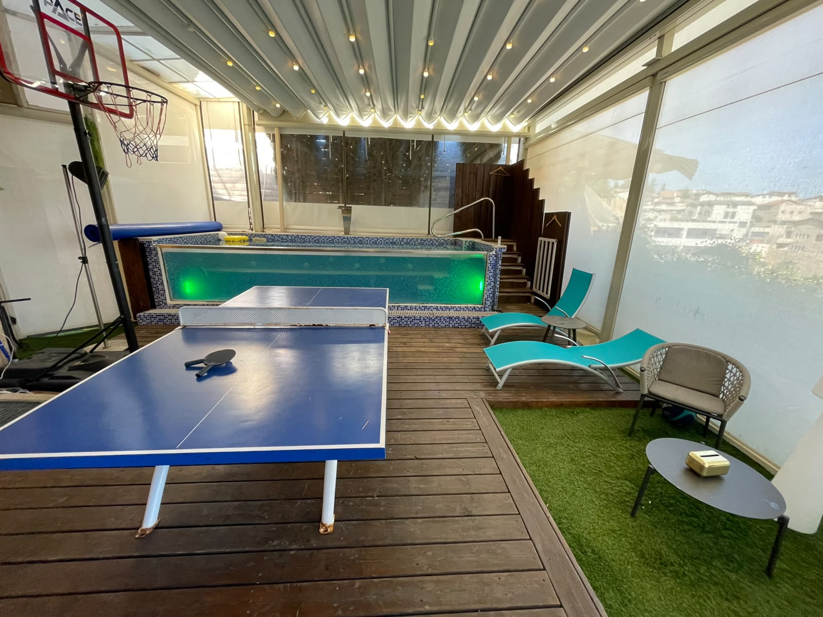 Ping pong table with pool and basketball hoop in background