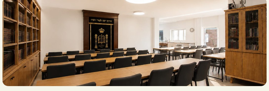 The Beit Midrash with rows of wooden tables, chairs, and bookshelves